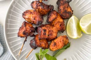 air fryer tandoori chicken on a plate with lemon and mint.