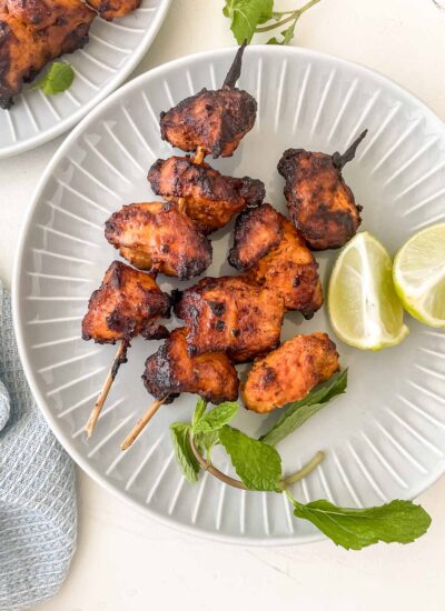 air fryer tandoori chicken on a plate with lemon and mint.