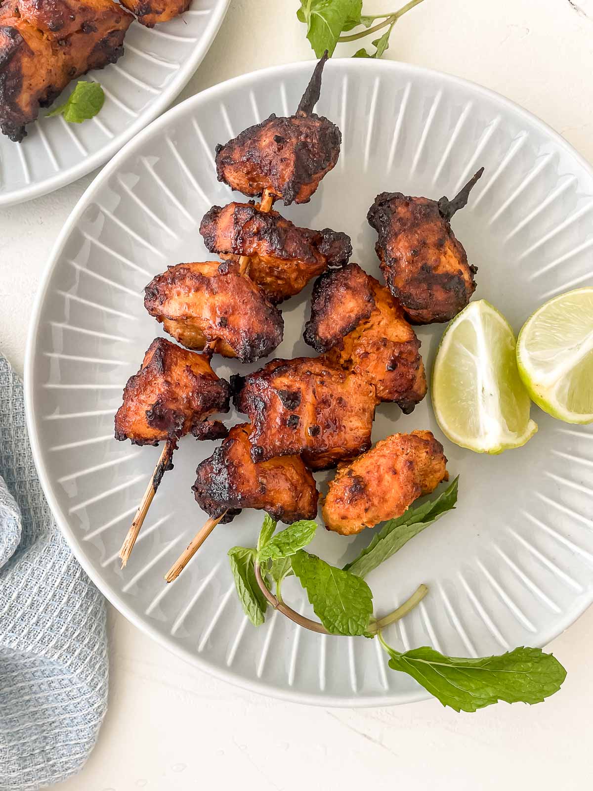 air fryer tandoori chicken on a plate with lemon and mint.