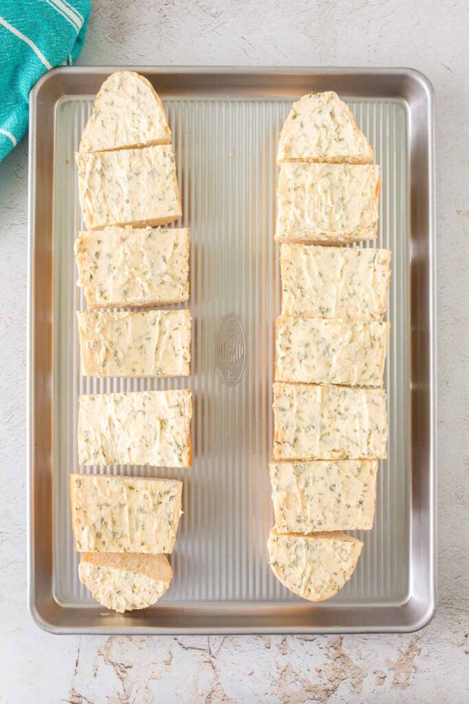 unbaked garlic bread pieces on a baking tray.