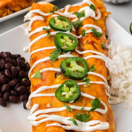 chicken enchiladas on a plate topped with jalapenos.