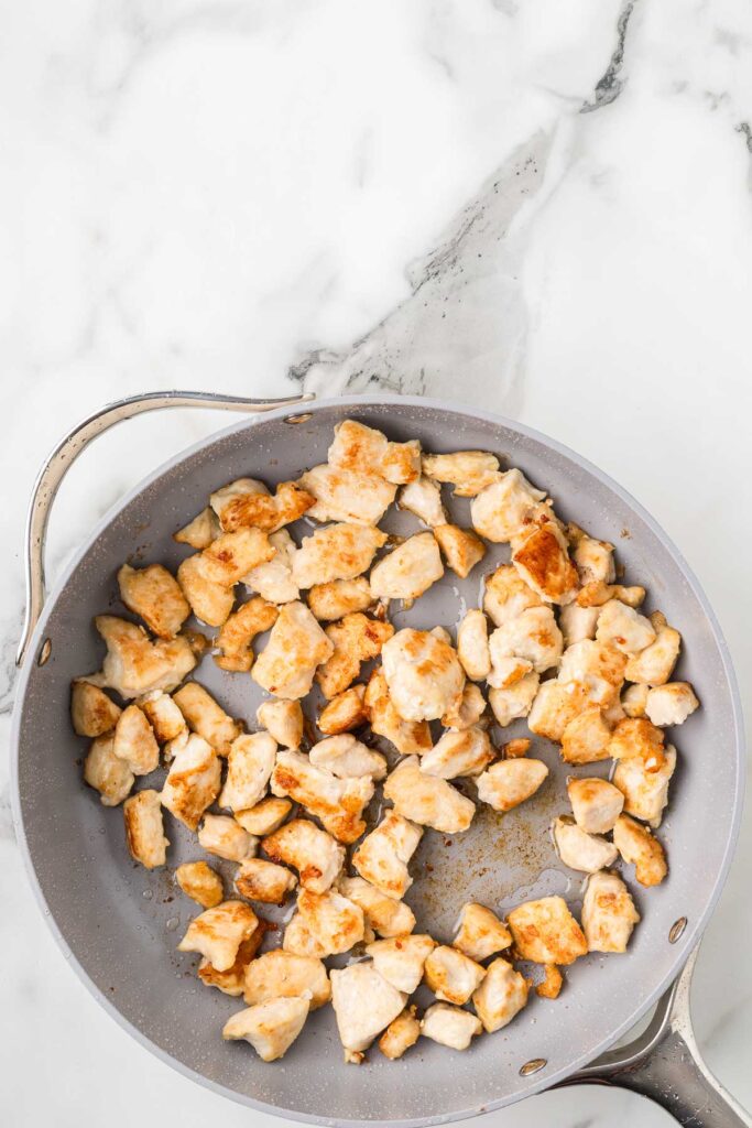 chicken browning in a pan.