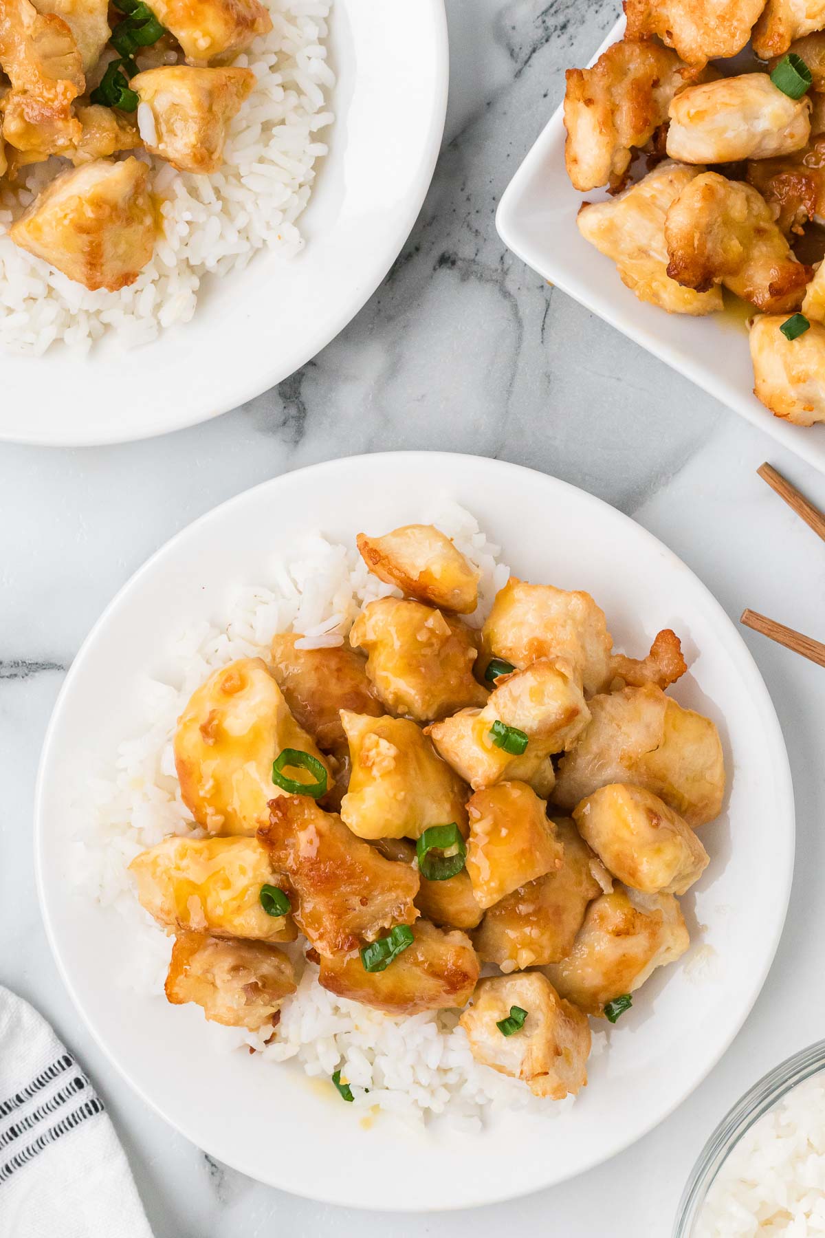 orange chicken on a plate on top of white rice.