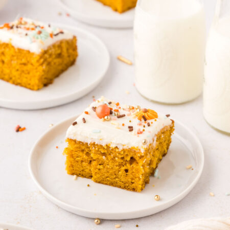 3 plates with pumpkin bars with cream cheese frosting next to milk bottles.